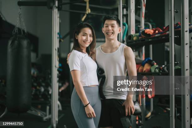 asian chinese athlete couple side by side looking at camera smiling in gym after workout - tough love stock pictures, royalty-free photos & images