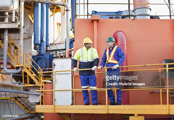 workers talking on oil rig - railings 個照片及圖片檔