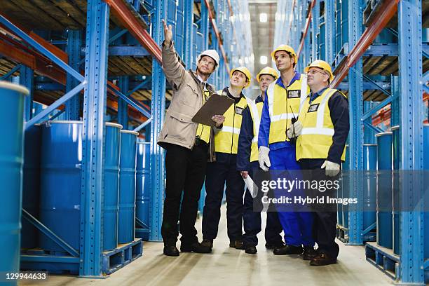 arbeiter sprechen im warehouse - arbeitssicherheit stock-fotos und bilder