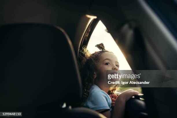 little girl looking in the car window at sunset - girl thinking stock pictures, royalty-free photos & images