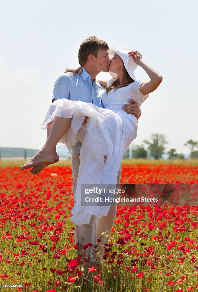 Couple kissing in field of poppies