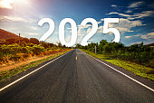 The word 2025 behind the tree of empty asphalt road at golden sunset and beautiful blue sky.