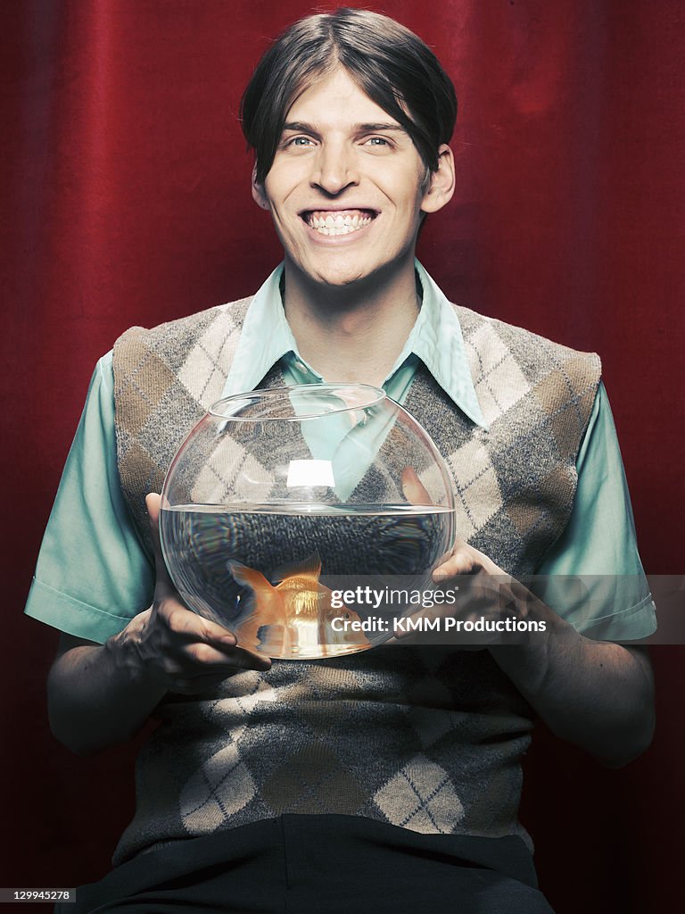 Smiling man holding fishbowl
