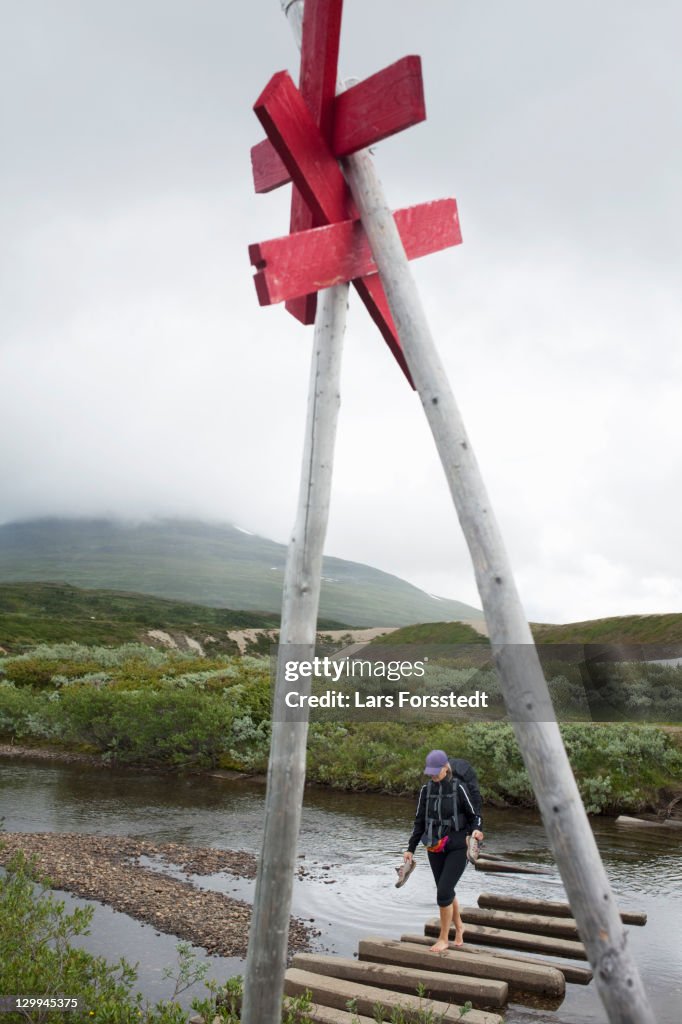 Hiker walking on logs over river