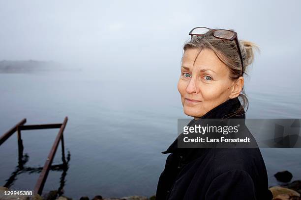 woman smiling by still lake - vrouw 50 jaar stockfoto's en -beelden
