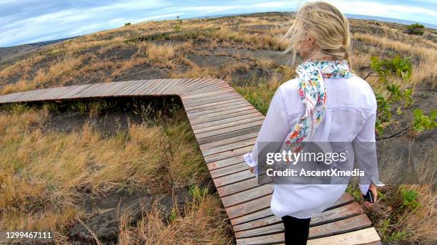 woman walks down boardwalk above petroglyphs - hawaiian women weaving stock pictures, royalty-free photos & images