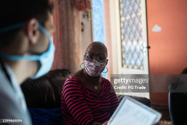 doctor talking to patient during a home vist - wearing face mask - social worker mask stock pictures, royalty-free photos & images