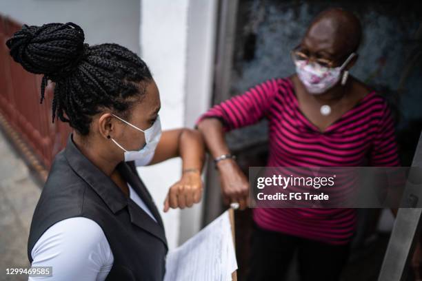 surveyor greeting senior woman in the doorway - wearing face mask - door to door salesperson stock pictures, royalty-free photos & images