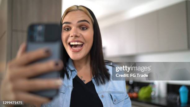 transgender woman doing a video call on smartphone at home - influencer phone stock pictures, royalty-free photos & images