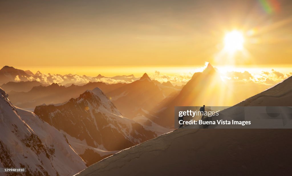 Climbers on a snowy ridge at sunrise