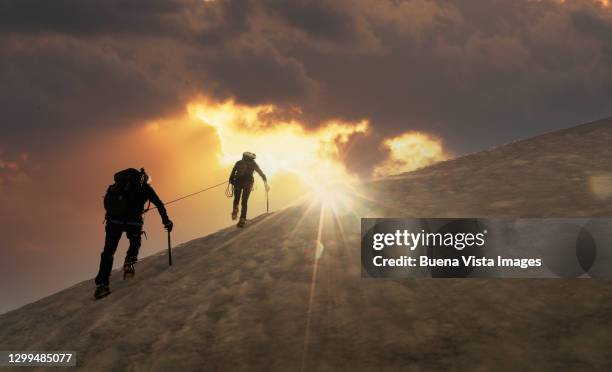 climber on a snowy slope at sunrise - berg klimmen team stockfoto's en -beelden