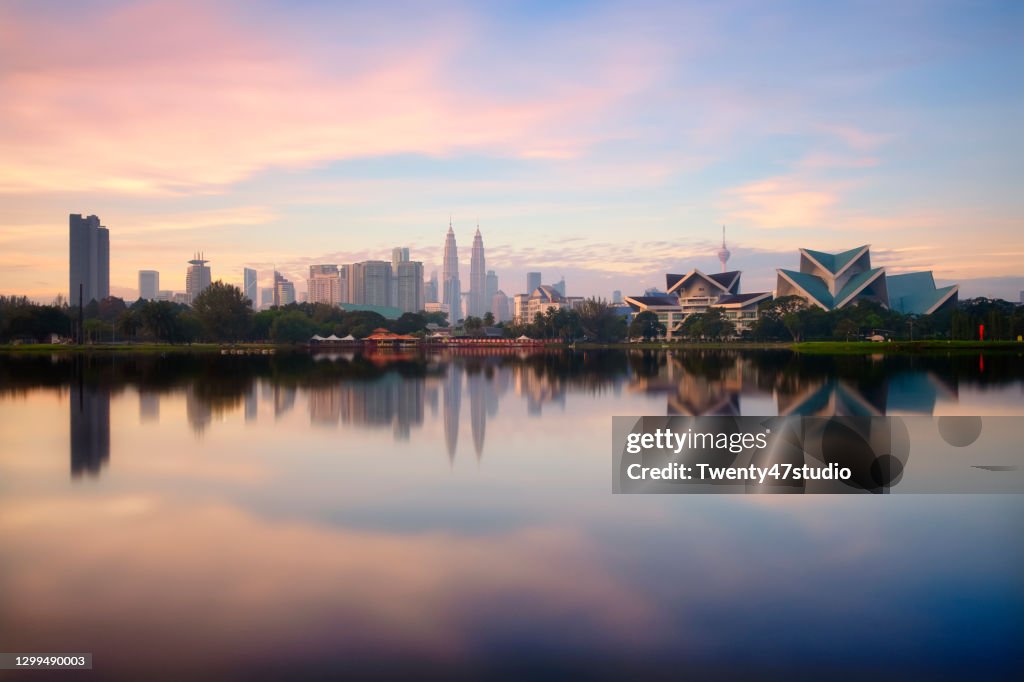 Panoramic Kuala Lumpur cityscape reflects on lake from Titiwangsa park in Malaysia