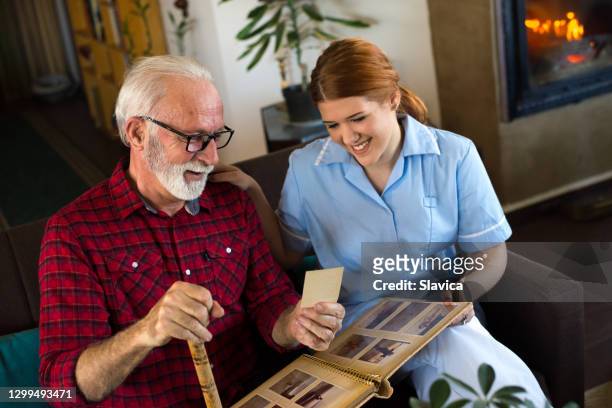 senior man bonding with nurse - memories stock pictures, royalty-free photos & images