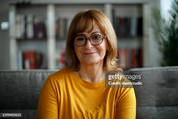 retrato de una mujer mayor sonriente en casa - 55 59 años fotografías e imágenes de stock