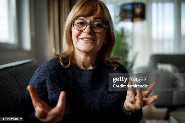 sonriente mujer mayor hablando en videollamada en casa - businesswoman couch fotografías e imágenes de stock