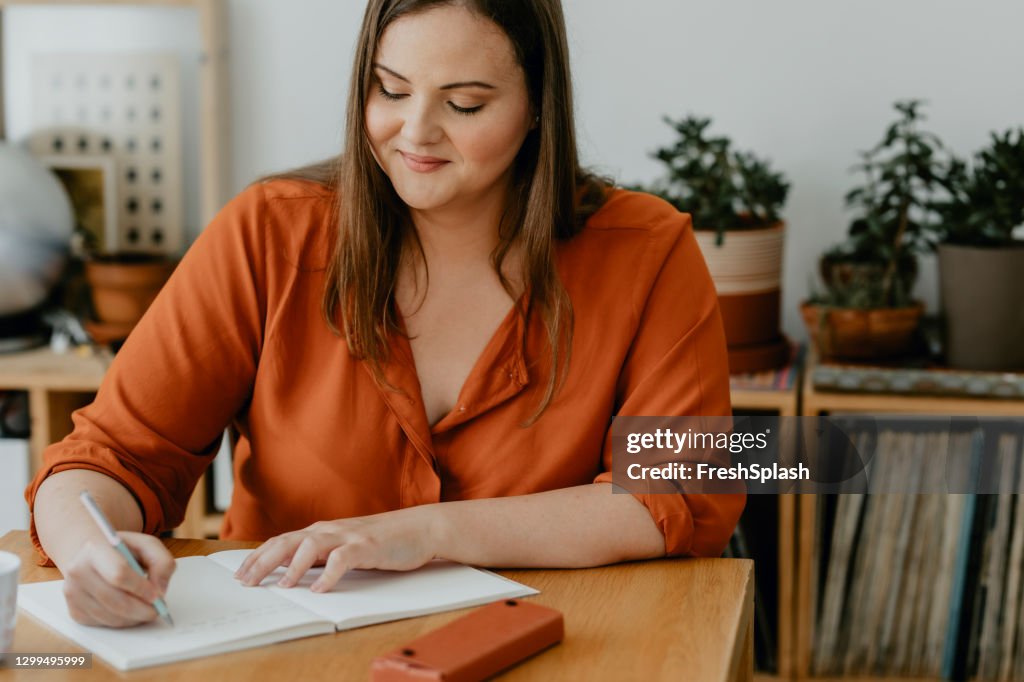 Beautiful plus size Woman Sitting in her Living Room and Writing a Diary