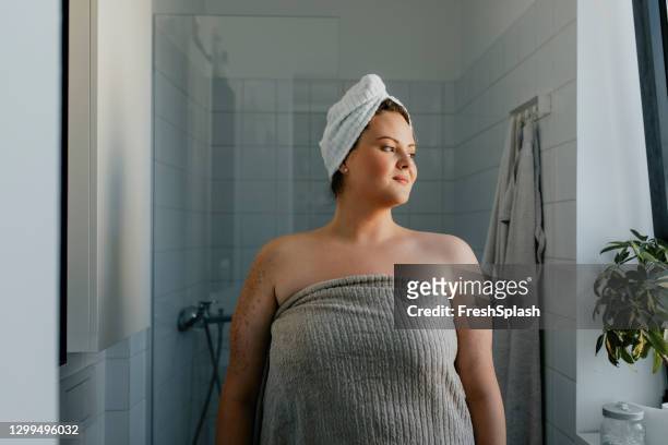 portrait of a happy  plus size woman standing in the bathroom after a relaxing shower - women taking showers stock pictures, royalty-free photos & images