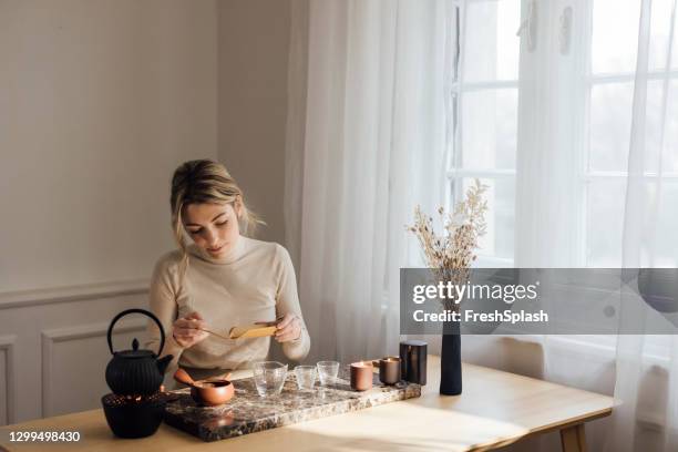 traditional tea making: a beautiful young blonde woman making herself tea - steep stock pictures, royalty-free photos & images