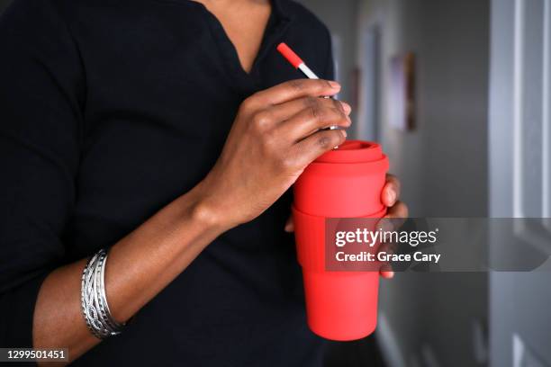 woman enjoys drink using reusable cup and straw - black mug stock pictures, royalty-free photos & images