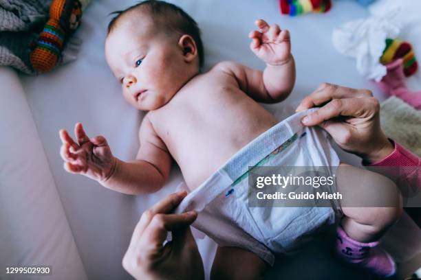 mother changing diaper of her baby on diaper changing table. - diaper change stock-fotos und bilder