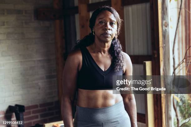 portrait of mature woman standing in cross training gym - irréductibilité photos et images de collection