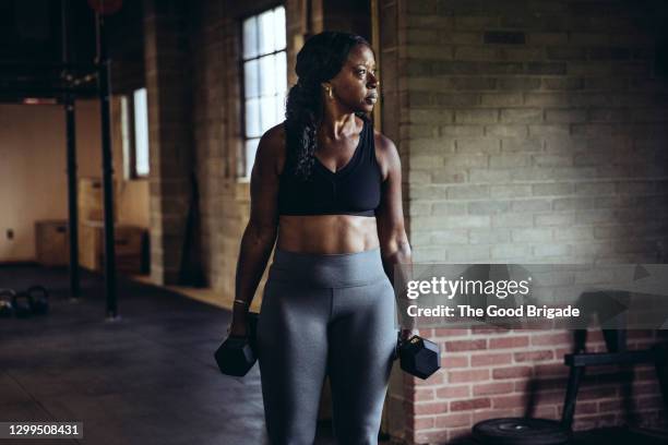 portrait of mature woman holding dumb bells at gym - dumbbell stock-fotos und bilder