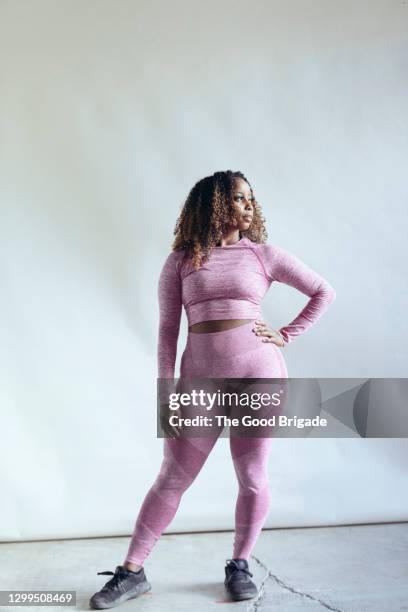 portrait of female body builder against white background - pink pants stockfoto's en -beelden