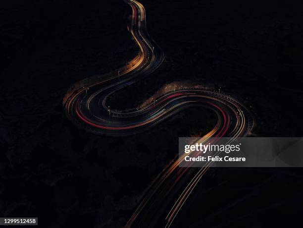 aerial view of car light trails on a winding road during the night. dark mode wallpaper. - control photos et images de collection