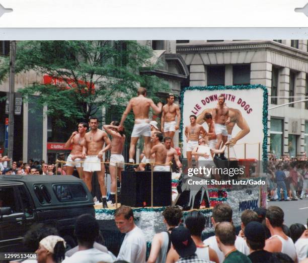 Spectators line Fifth Avenue, watching muscular men wearing white boxers ride on a float advertising the film Lie Down with Dogs, participating in...