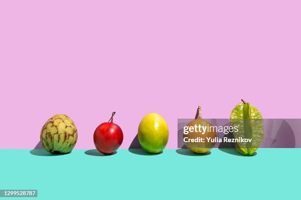 variation of tropical fruits (tamarillo,carambola, passion fruit, cherimoya,passiflora singularis/grenadilla, mara)  on the rose- turquoise background - coloured light patterns in a studio environment stock pictures, royalty-free photos & images