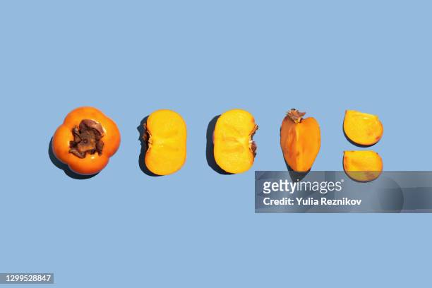 fuyu persimmons (khaki fruits) on the blue background - khaki stock pictures, royalty-free photos & images