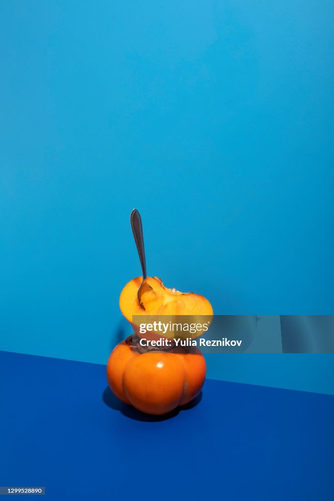 Fuyu Persimmons (Khaki fruits) with spoon on the blue background