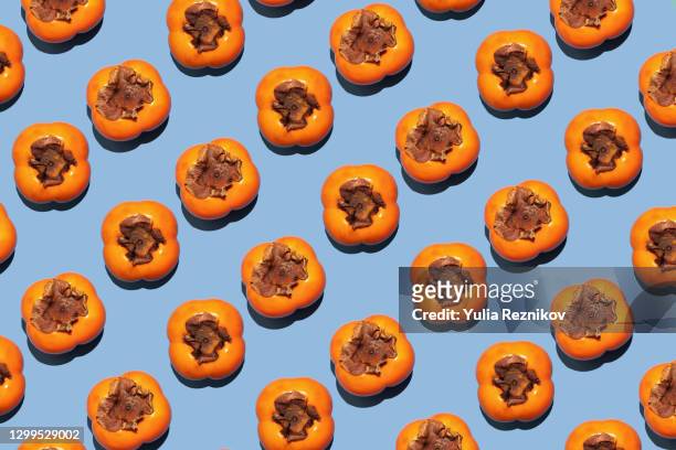 repeated persimmon fruits on the blue background - khaki stock pictures, royalty-free photos & images