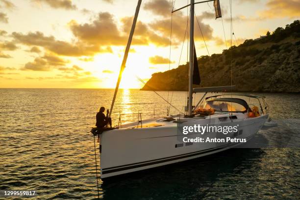 girl sitting on the bow of a yacht at sunset in the sea - pasear en coche sin destino fotografías e imágenes de stock