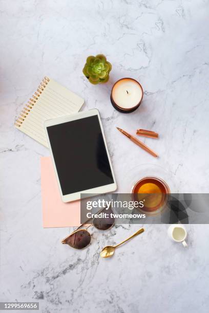 flat lay daily objects, digital tablet, tea cup and house plant on marble coffee table top still life. - sunglasses overhead fotografías e imágenes de stock