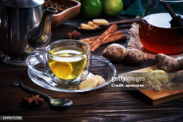 high angle close-up view of a cup of hot tea ginger infusion on a table in a rustic kitchen - ginger tea stock pictures, royalty-free photos & images