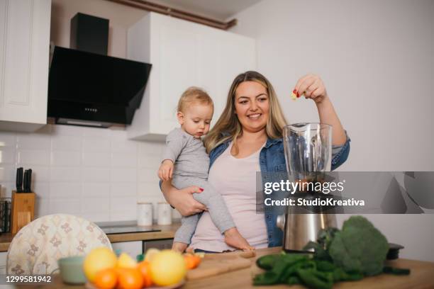 young mother is feeding her baby - alleinerzieherin stock pictures, royalty-free photos & images