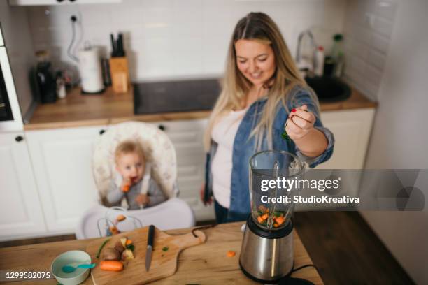 young mother is feeding her baby - alleinerzieherin stock pictures, royalty-free photos & images