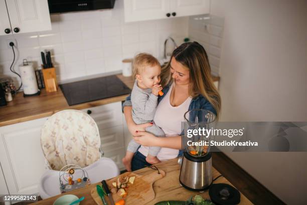 young mother is feeding her baby - ein elternteil stock pictures, royalty-free photos & images