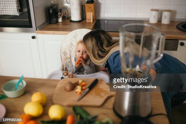 young mother is feeding her baby - alleinerzieherin stock pictures, royalty-free photos & images
