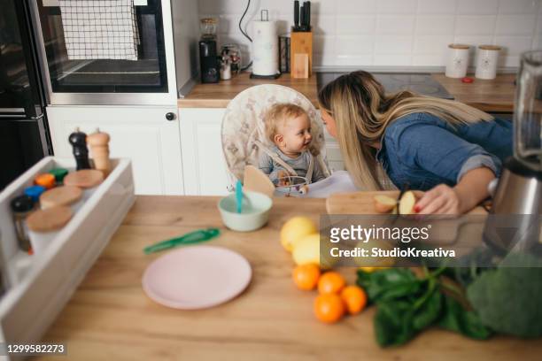 young mother is feeding her baby - ein elternteil stock pictures, royalty-free photos & images