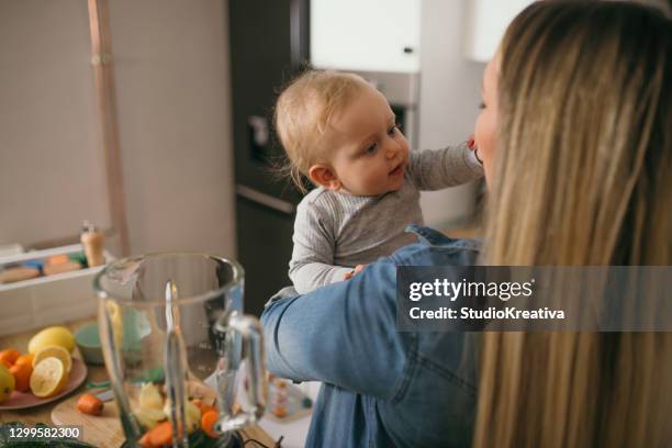 young mother is feeding her baby - ein elternteil stock pictures, royalty-free photos & images