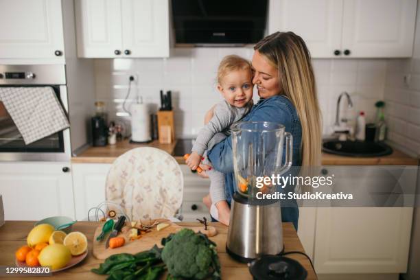 young mother is feeding her baby - ein elternteil stock pictures, royalty-free photos & images