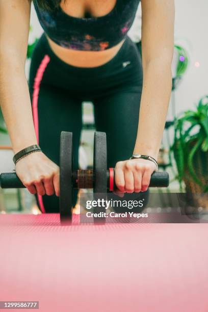 medium shot of young hispanic woman doing exercise with gym wheel - pectoral muscle women stock pictures, royalty-free photos & images