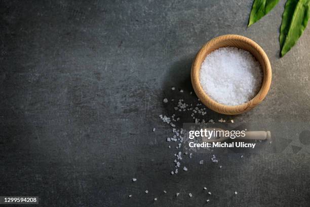 sea salt on black background. salt in the wooden bowl and green decoration. - saliera foto e immagini stock