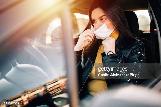 young woman driving car with protective mask on her face - allergens car stock pictures, royalty-free photos & images