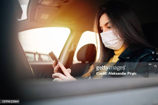 young woman driving car with protective mask on her face - allergens car stock pictures, royalty-free photos & images