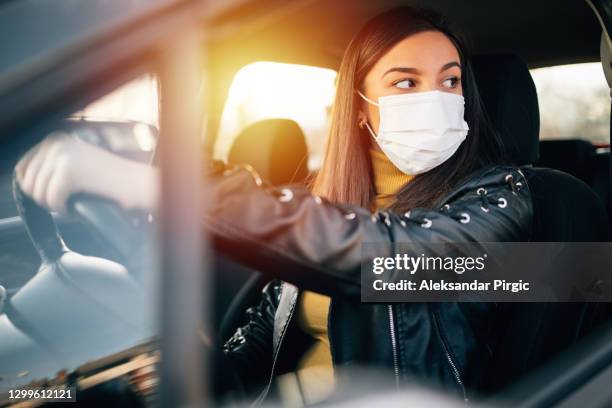 young woman driving car with protective mask on her face - allergens car stock pictures, royalty-free photos & images