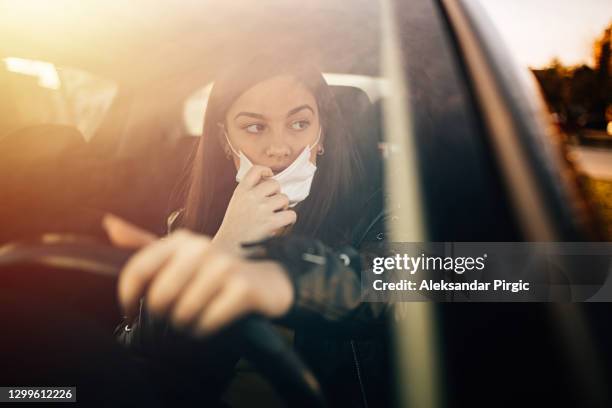 young woman driving car with protective mask on her face - allergens car stock pictures, royalty-free photos & images