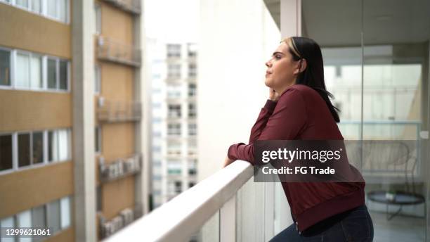 donna transgender nel balcone dell'appartamento guardando la vista - one young woman only foto e immagini stock